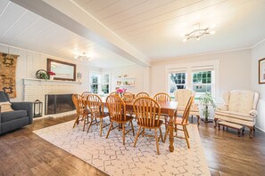 A dining area with a wooden table and chairs, a fireplace, and a view of the outdoors.