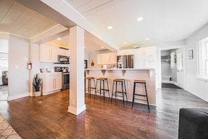 A modern kitchen with white cabinets, stainless steel appliances, and wooden stools.