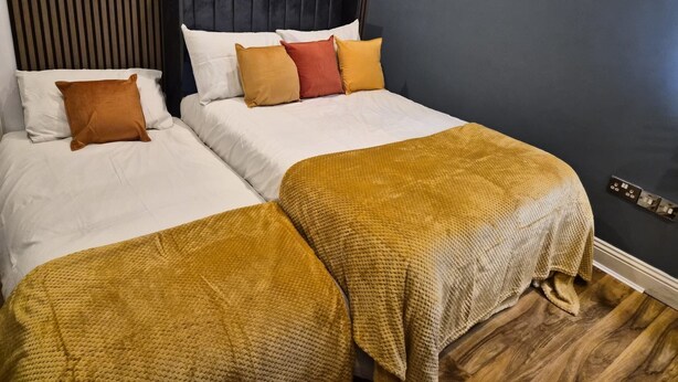Una cama doble con cabecera oscura y dos mesitas de noche.