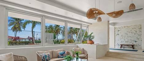 A modern living room with large windows, a sofa, a coffee table, and a hanging light fixture.