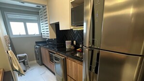 Une cuisine moderne dotée d’appareils électroménagers en acier inoxydable, d’un plan de travail noir et d’un tapis vert.