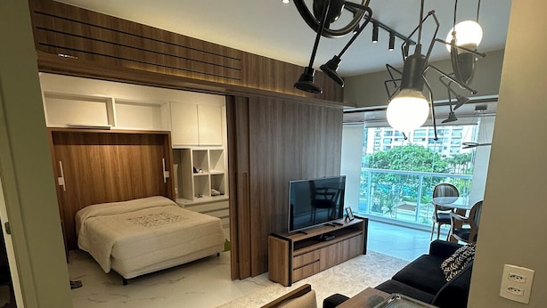 Une chambre moderne avec un lit, une télévision et un balcon offrant une vue agréable.