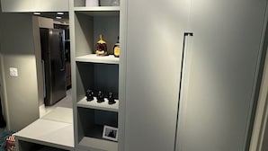 Une cuisine moderne avec des meubles gris, un four encastré et un plan de travail en marbre.