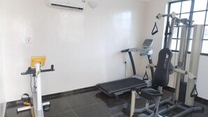 A gym with a treadmill, weight machine, and a bench. - DAVIES SUITES  (Enugu)