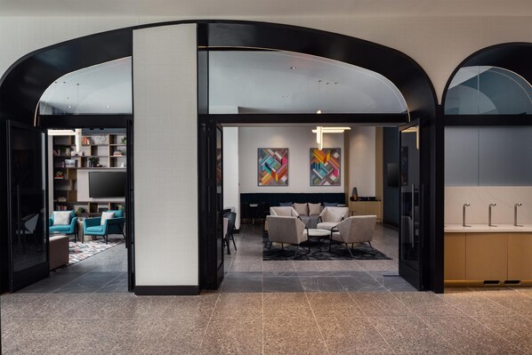 A modern interior with a central seating area, a kitchen, and a living room with a large TV. - Tempo By Hilton Washington Dc Downtown (Washington)