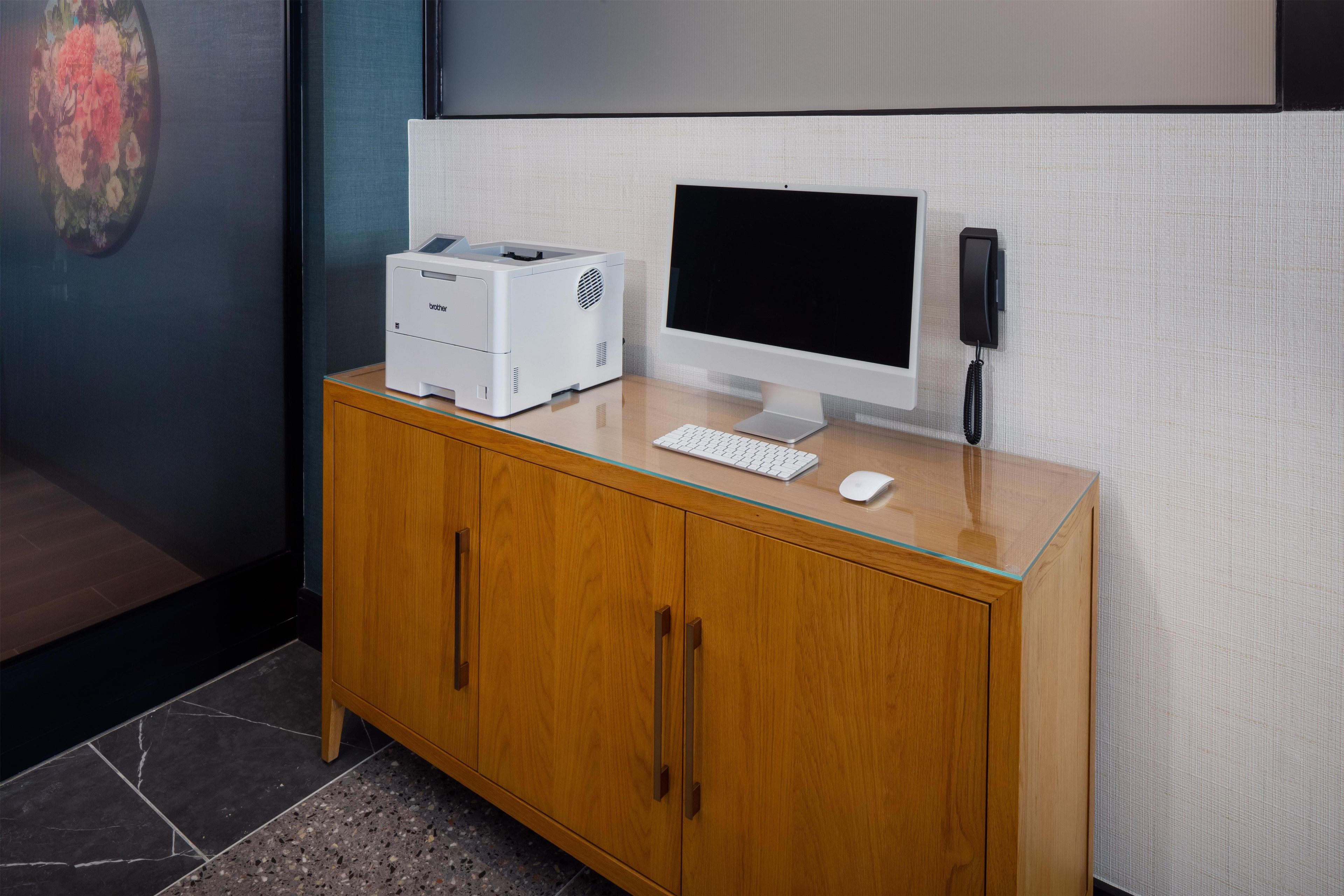 Un meuble en bois contenant un ordinateur de bureau, une imprimante et un téléphone.