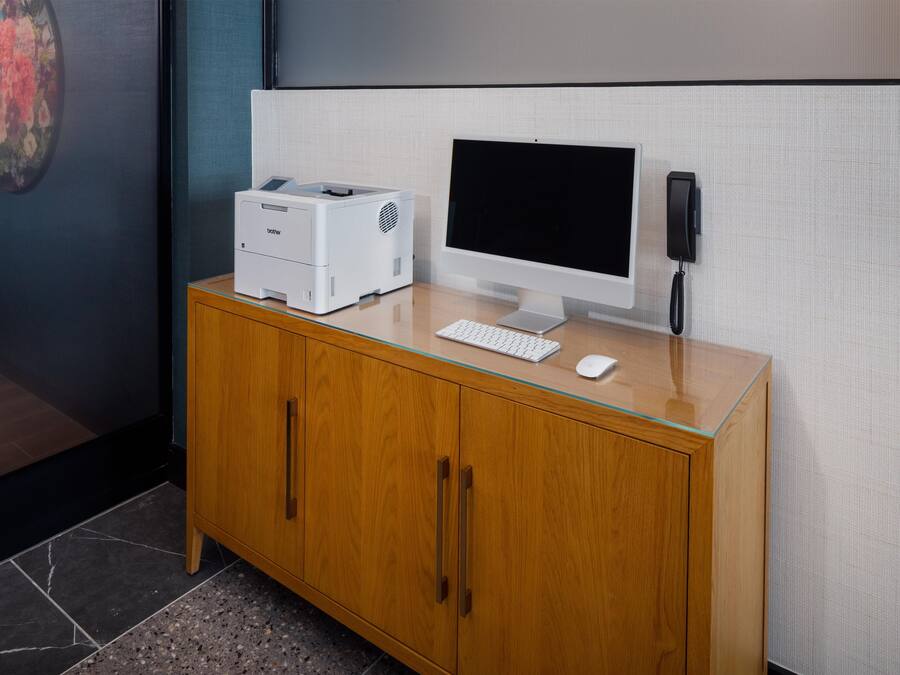 Un meuble en bois contenant un ordinateur de bureau, une imprimante et un téléphone.