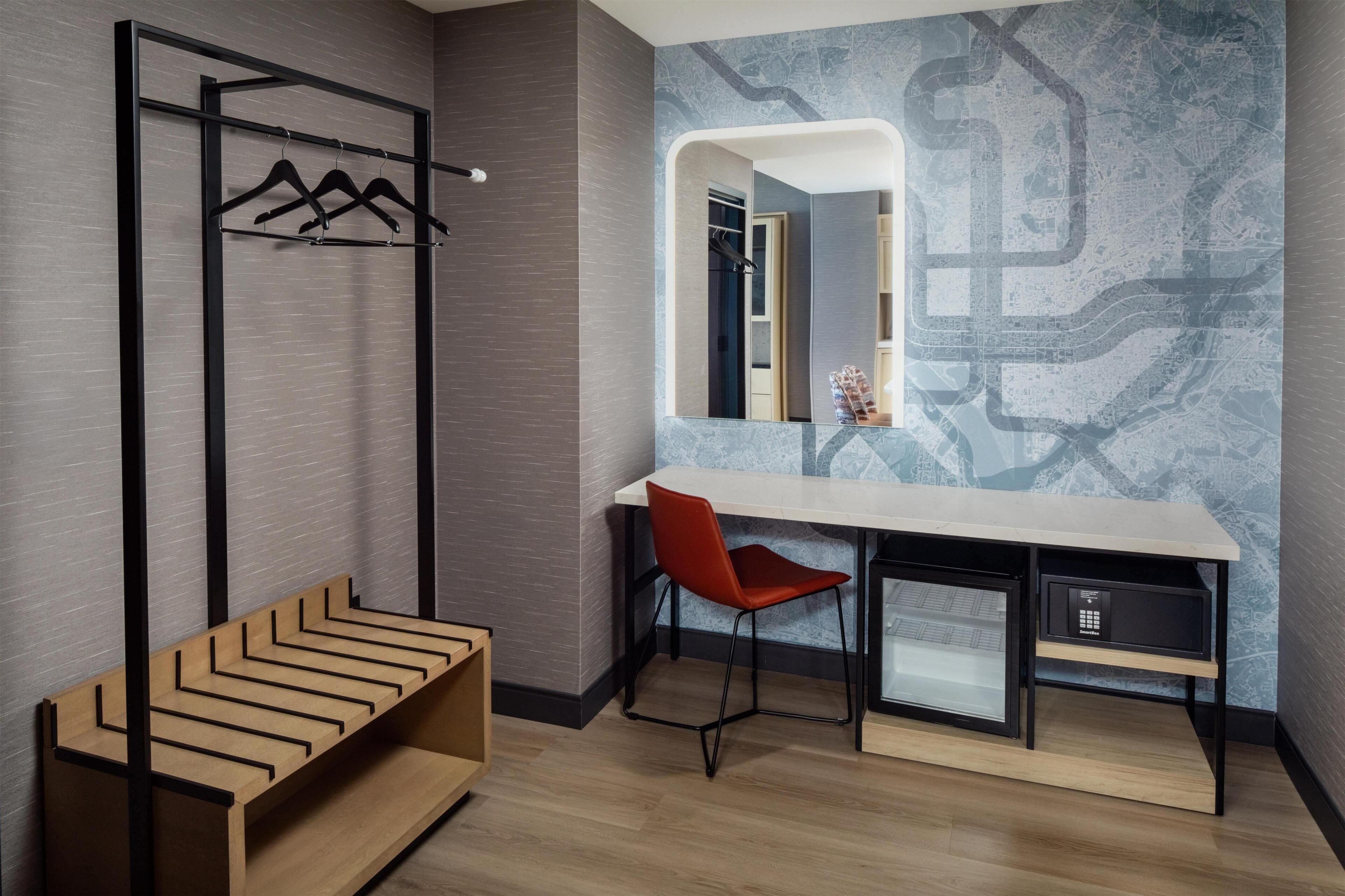 A modern room with a desk, chair, and a coat rack.