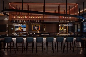 Un espace bar moderne doté d’un îlot central, de tabourets de bar et d’un plafond décoratif.