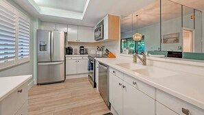 A modern kitchen with white cabinetry, stainless steel appliances, and a skylight. - Wild Pines A307 (Bonita Springs)