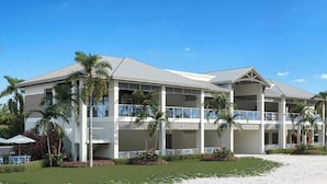 A multi-story hotel with balconies, palm trees, and a sandy beach. - Wild Pines A307 (Bonita Springs)