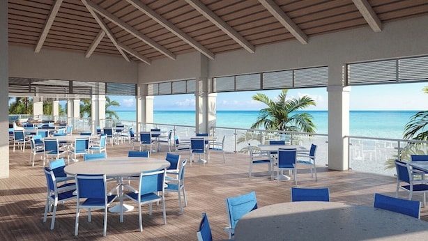 An outdoor dining area with tables and chairs, overlooking a beach. - Wild Pines A307 (Bonita Springs)