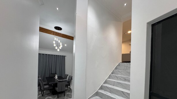 Ein modernes Interieur mit einer Marmortreppe, die zu einem Essbereich mit Tisch und Stühlen führt.