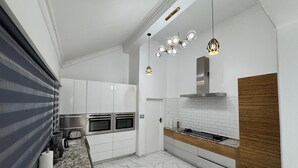 Eine moderne Küche mit weißen Schränken, einem eingebauten Ofen, einem Herd und einer Holz Arbeitsplatte.