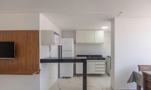 A compact kitchen with a microwave, refrigerator, and a built-in oven. - Apartments Just 270 Meters From Praia do Morro, Guarapari - Epus (Guarapari)