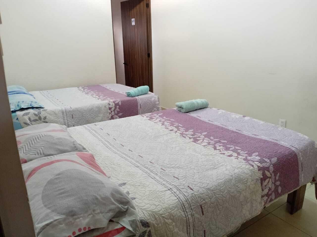 A room with two beds, each with a patterned bedspread and pillows.