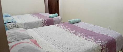 A room with two beds, each with a patterned bedspread and pillows.