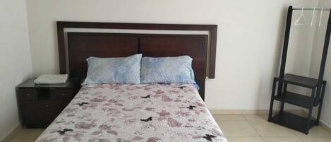 Une chambre à coucher comprenant un lit, une table de chevet, une tête de lit en bois et une étagère en métal noir.