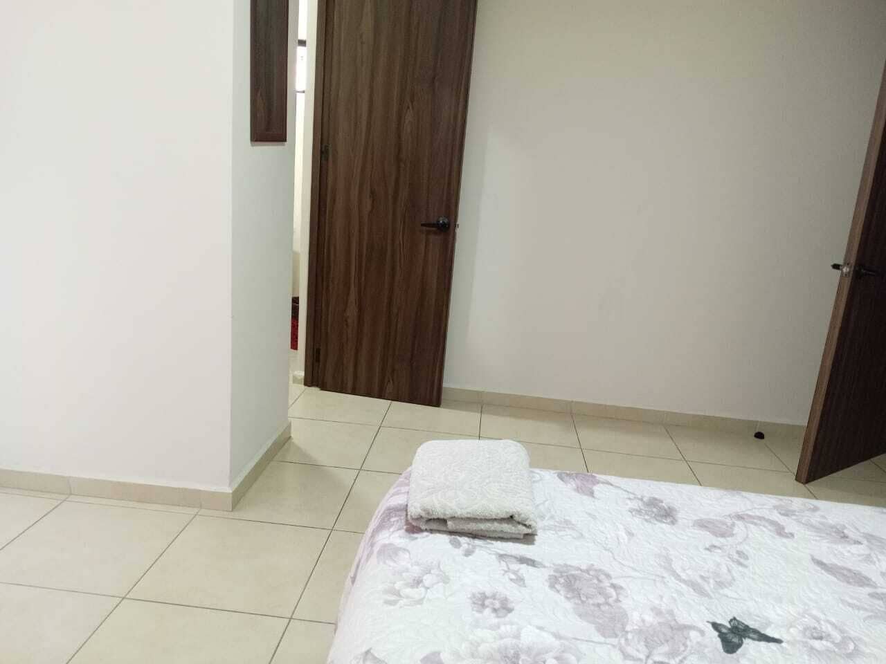 Un dormitorio con una cama, una puerta de madera y una pared blanca.