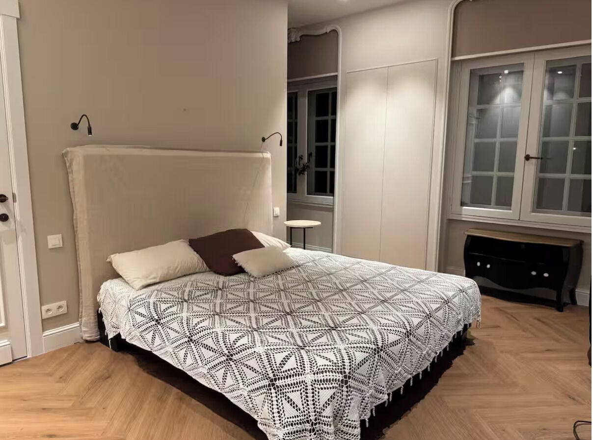 Ein Schlafzimmer mit einem großen Bett, einem Nachttisch, einem Kleiderschrank und einem Fenster mit Vorhängen.