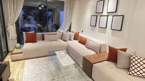 A modern living room with a sectional sofa, a glass coffee table, and a large window with curtains. - A haven of peace in Dar Bouazza (Casablanca)