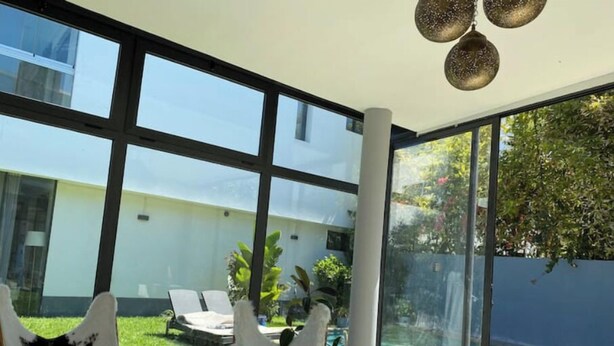 A modern interior with large windows, a pool, and outdoor seating. - A haven of peace in Dar Bouazza (Casablanca)