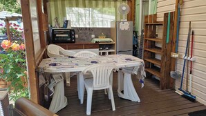 Un espacio al aire libre acogedor con mesa y sillas, un refrigerador y un ventilador.