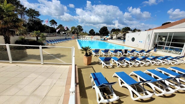 Zona de piscina con tumbonas y un cielo azul despejado.