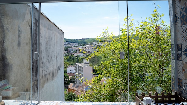 Una habitación con un amplio ventanal que ofrece vistas a un paisaje urbano y zonas verdes.