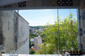 A room with a large window offering a view of a cityscape and greenery. - Casa Pet Friendly c 3 Quartos e Garagem no Jardim (Poços de Caldas)