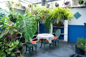 A small patio with a round table and two chairs, surrounded by various potted plants. - Casa Pet Friendly c 3 Quartos e Garagem no Jardim (Poços de Caldas)