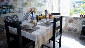 Un comedor con una mesa dispuesta para dos, un jarrón de flores y vista a un pueblo a través de una ventana.