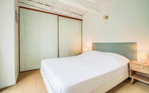 Ein Schlafzimmer mit Bett, Nachttisch, Lampe und Kleiderschrank.