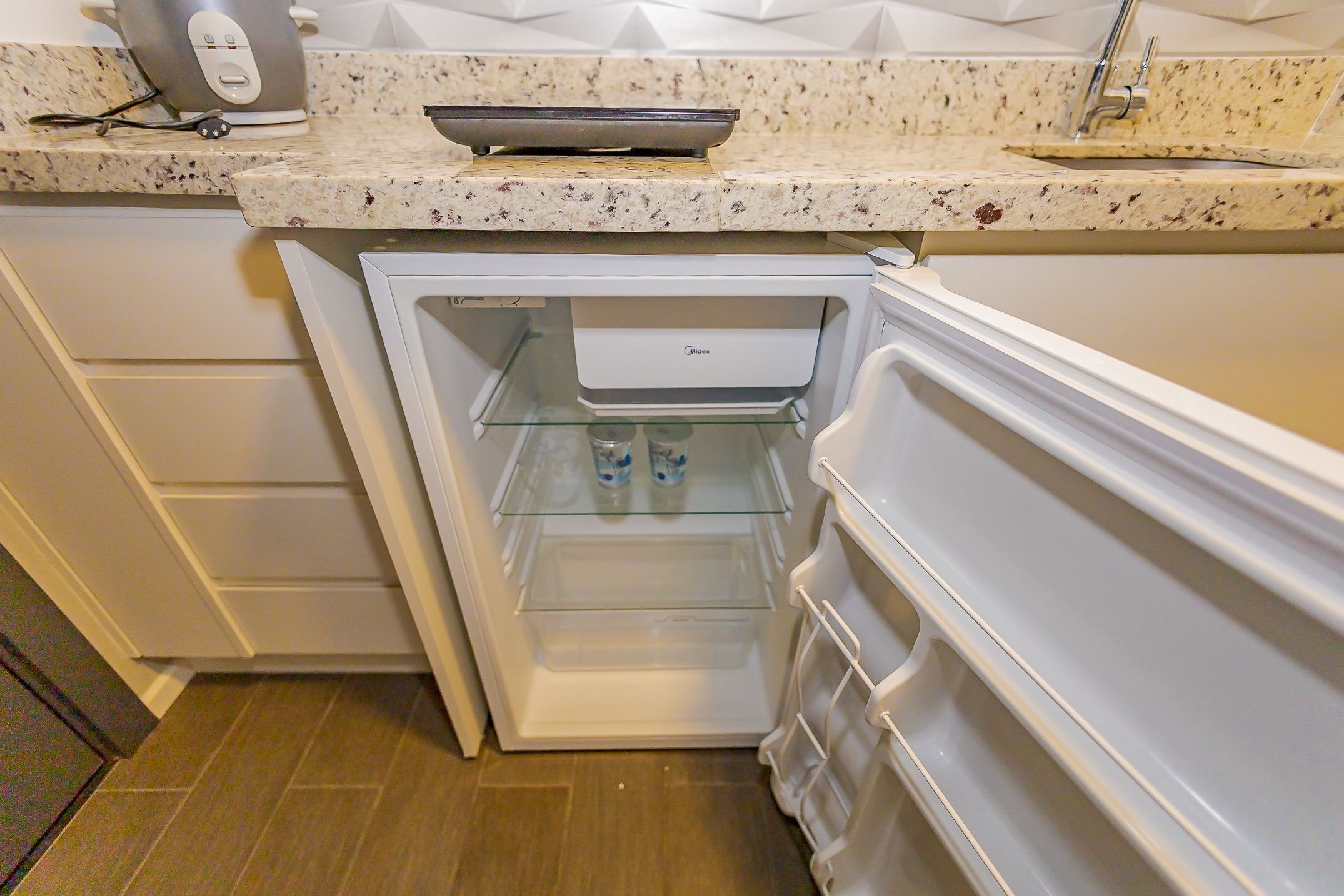 Cocina compacta con refrigerador integrado, microondas y pileta.