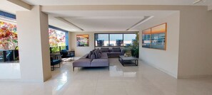 Una sala de estar moderna con un sofá seccional, una mesa de centro y un ventanal con vista a la ciudad.