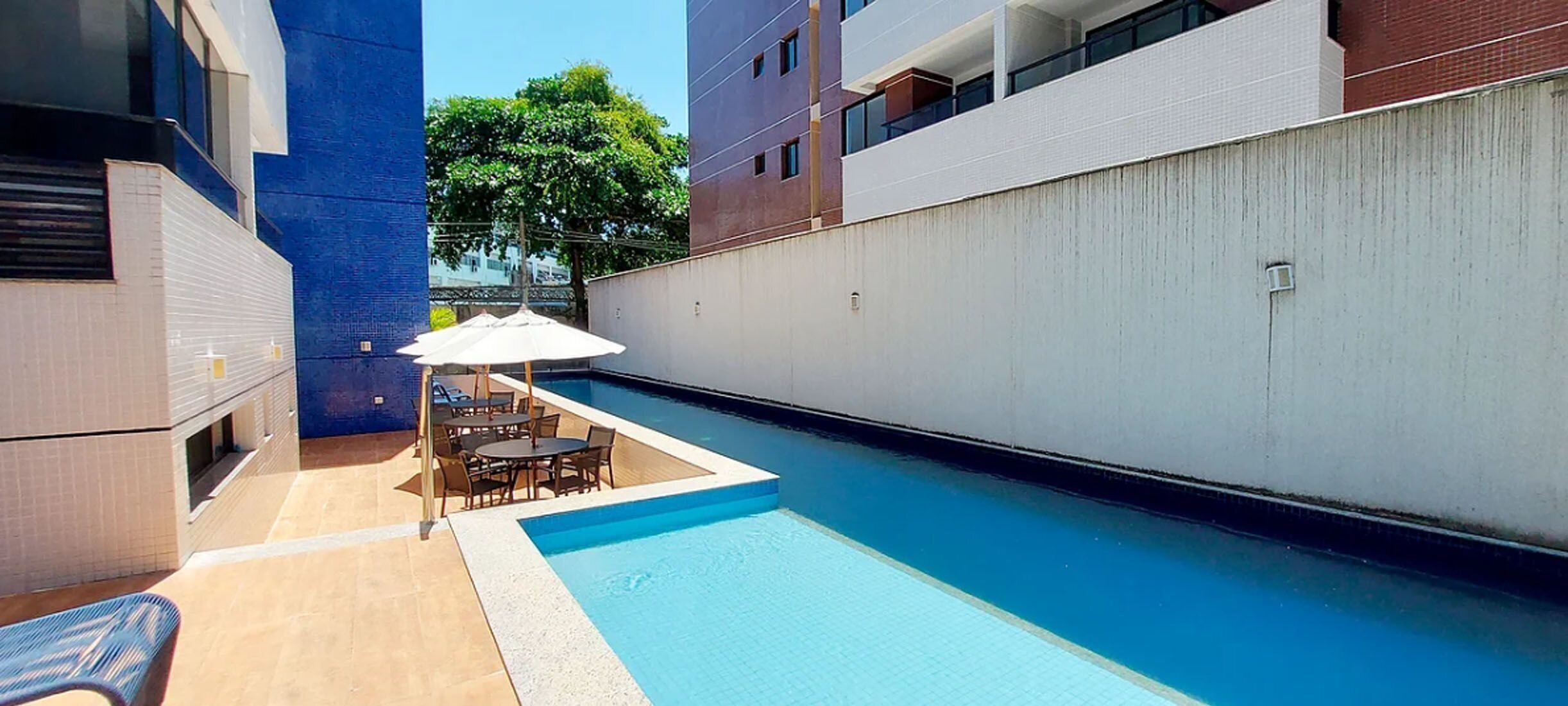 A swimming pool with a table and chairs, surrounded by buildings.