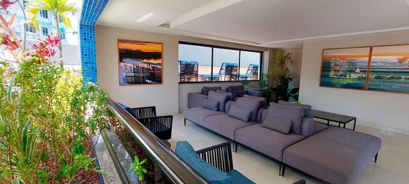 Una sala de estar moderna con un sofá gris, sillas negras y un ventanal con vistas a edificios.