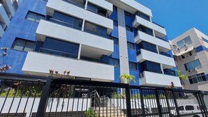 Un immeuble à plusieurs étages doté de balcons, d’une entrée sécurisée et surplombant un ciel dégagé.