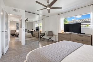A modern bedroom with a large bed, a desk, a chair, a television, and a ceiling fan. - Pet-friendly modern Sandstone Villas bungalow (Palm Springs)