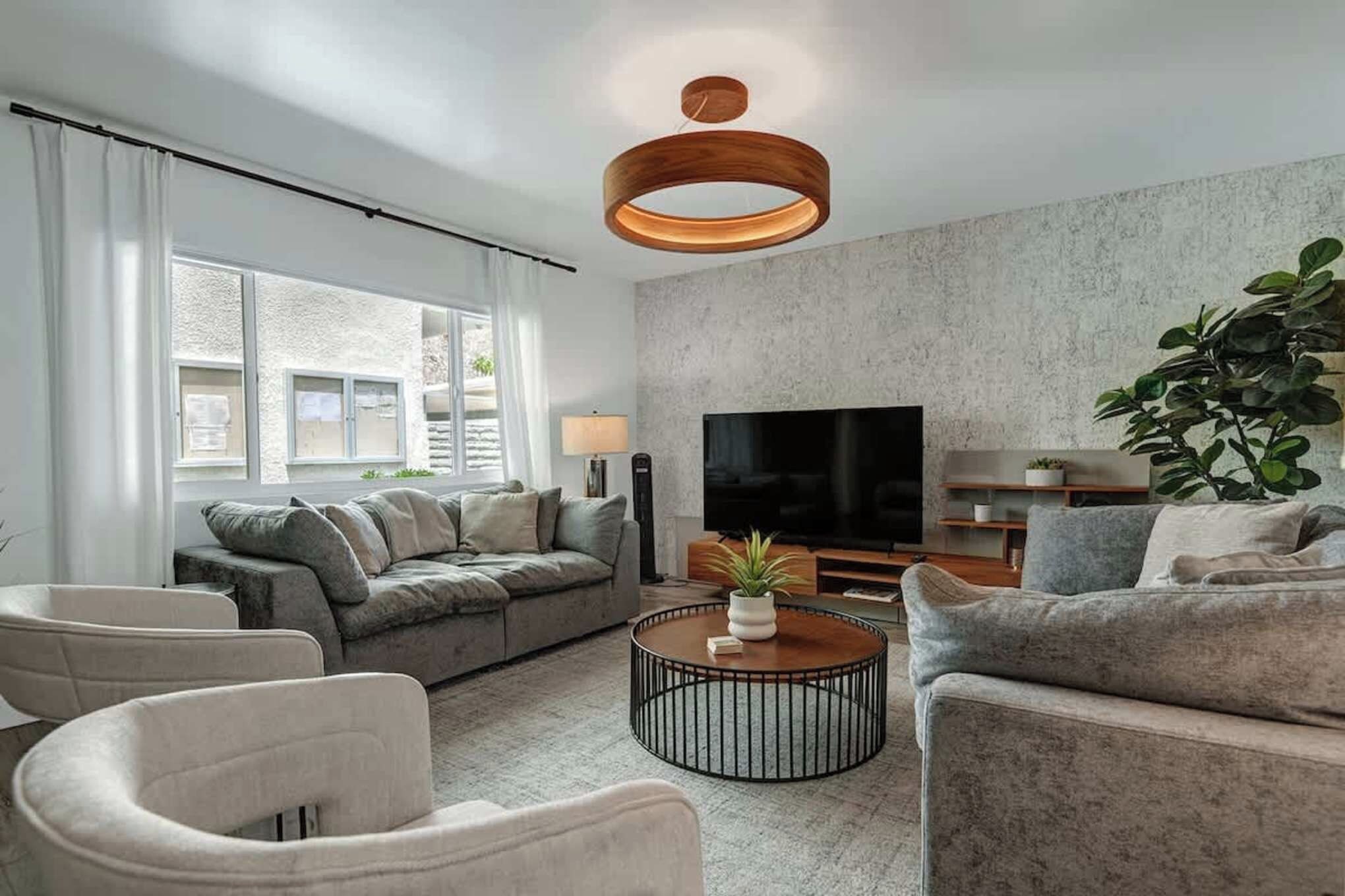 Sink into plush sofas and unwind in this serene living space, where soft textures, warm wood accents, and abundant natural light create the perfect retreat for your downtime.
