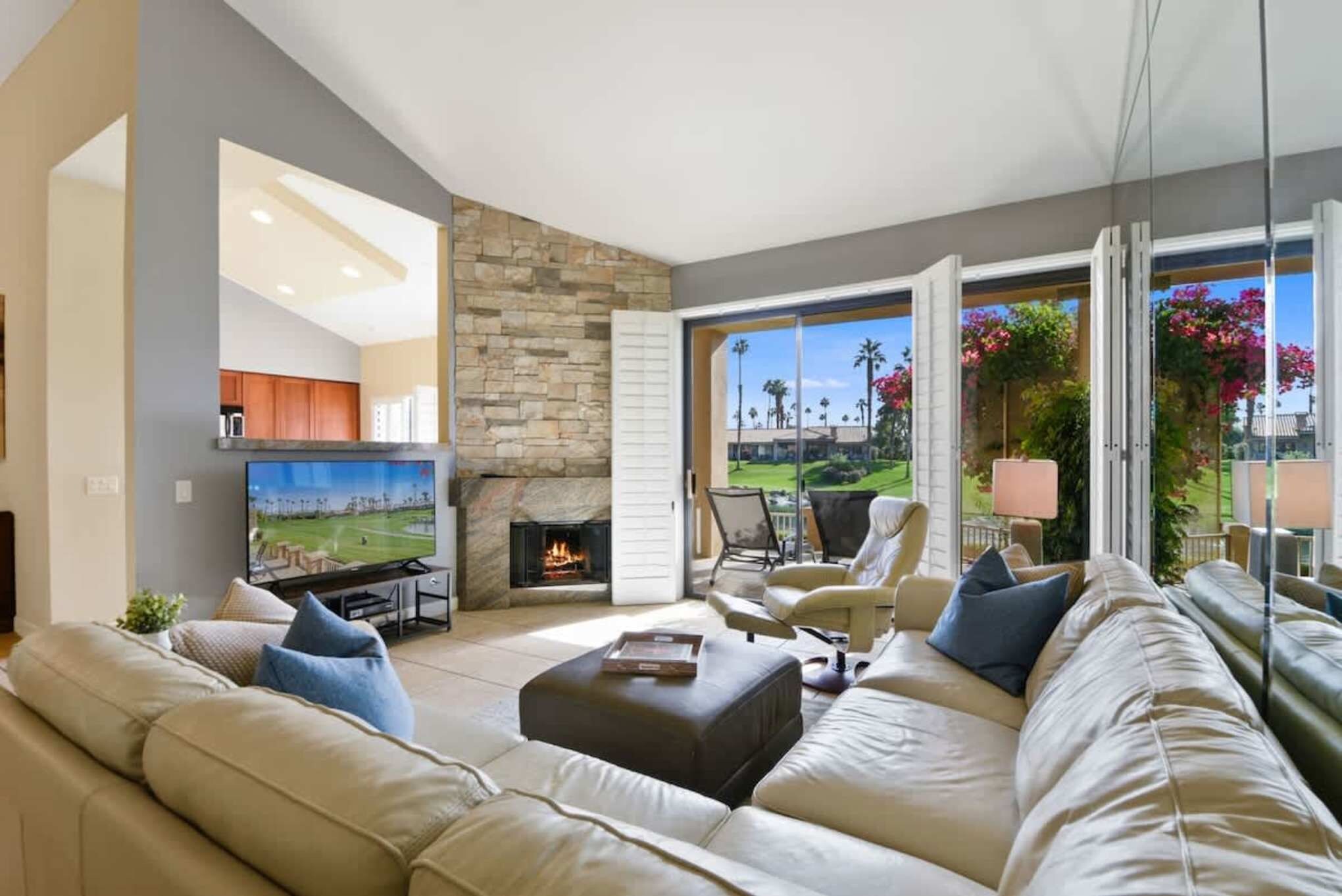 Sink into plush sofas and soak in peaceful greens through floor-to-ceiling windows. The stone fireplace and soaring ceilings create your own serene desert retreat.