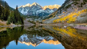 A mountain lake with reflections of the mountains and trees.