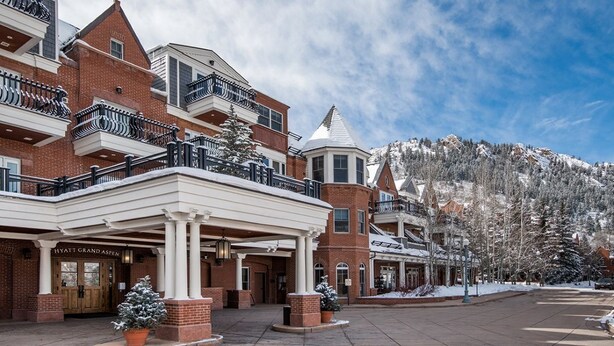 A hotel with a covered entrance, brick facade, and snow-covered trees in the background.