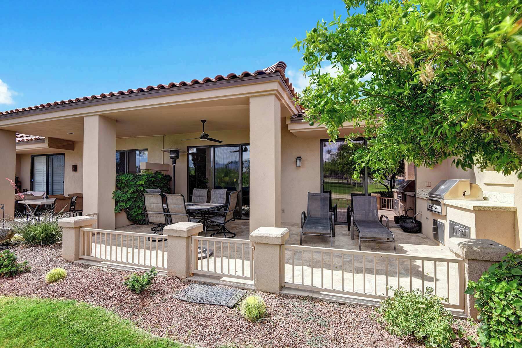 A covered patio area with outdoor seating, a ceiling fan, and a barbecue grill.