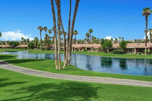 Un campo de golf con un estanque, palmeras y edificios de estilo resort.