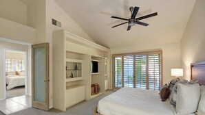 Un dormitorio con una cama grande, almacenamiento empotrado, ventilador de techo y vistas al exterior.