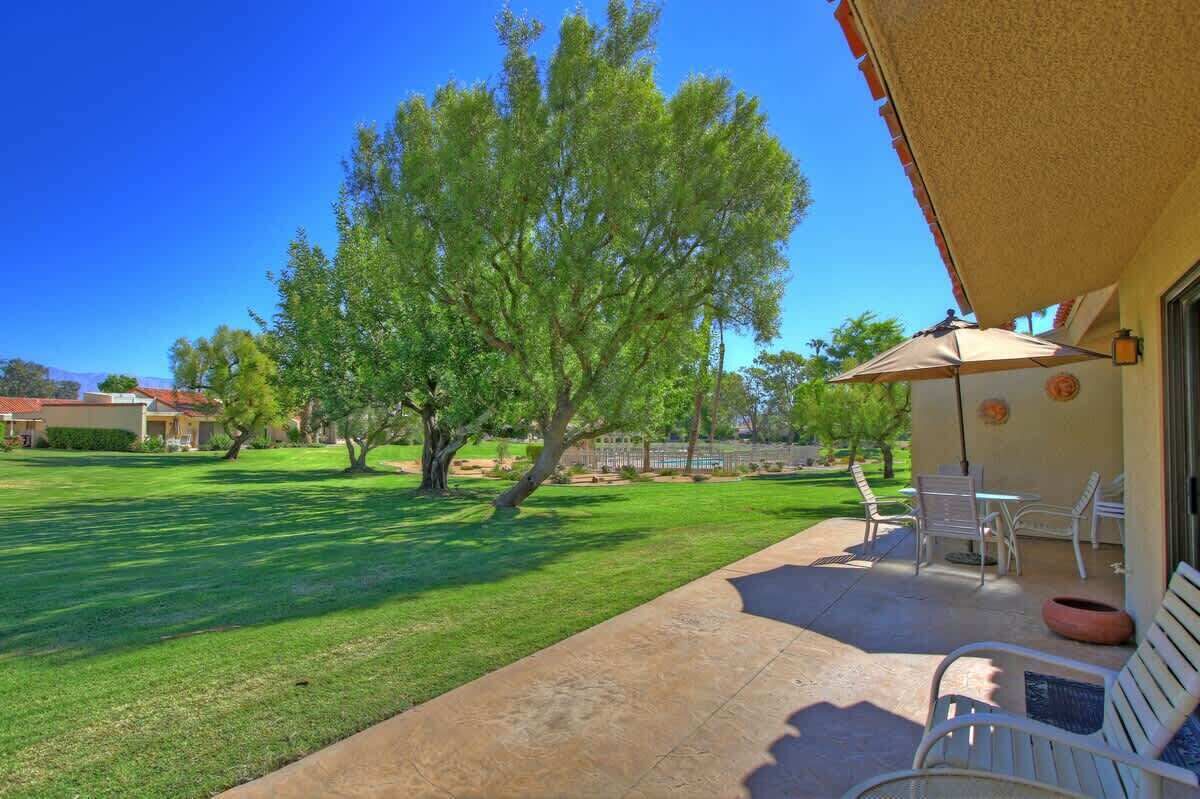 A patio area with outdoor furniture, a tree, and a building in the background.