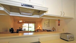 Cocina compacta con estufa integrada, tostadora y comedor con mesa y sillas.