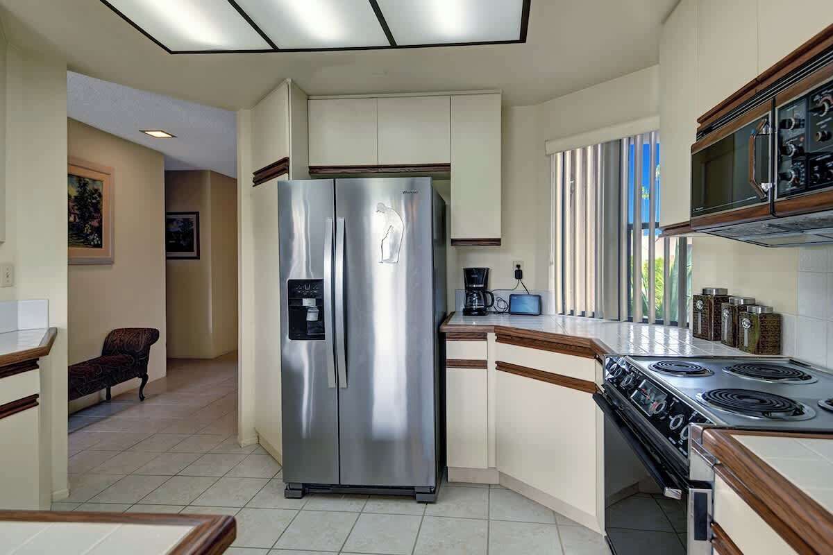 A modern kitchen with a stainless steel refrigerator, a stove, and wooden cabinets.