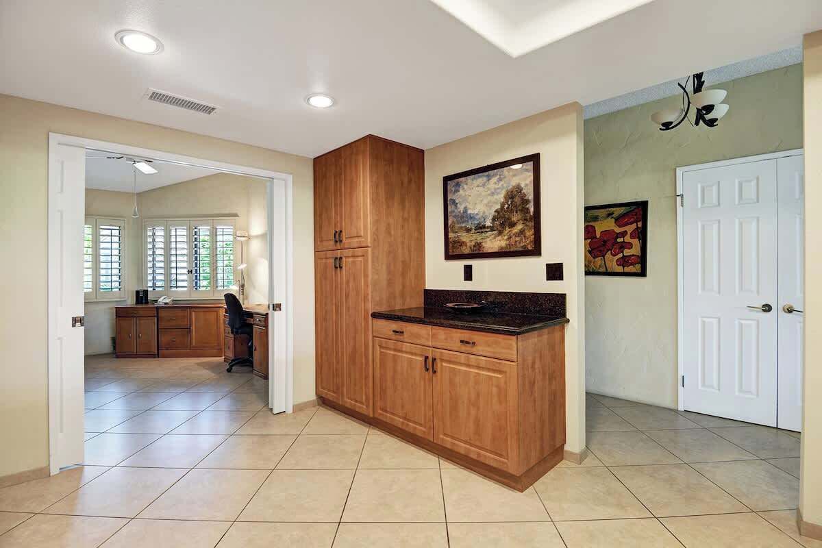 A spacious kitchen with wooden cabinets, a countertop, and a dining area with a chair.